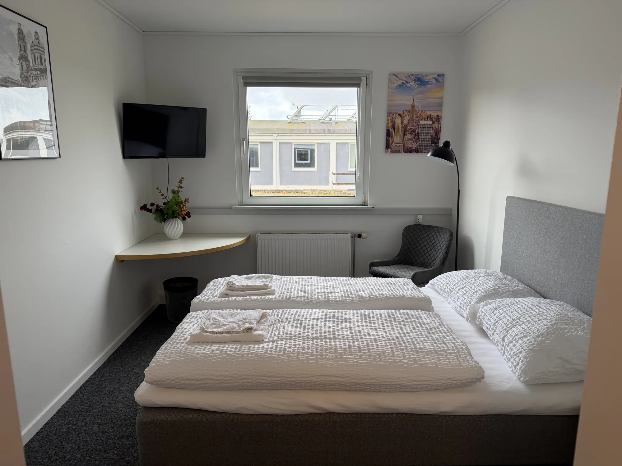 Dobbeltværelse på Motel Storstrøm med dobbeltseng, tv og bænk foran vinduet
