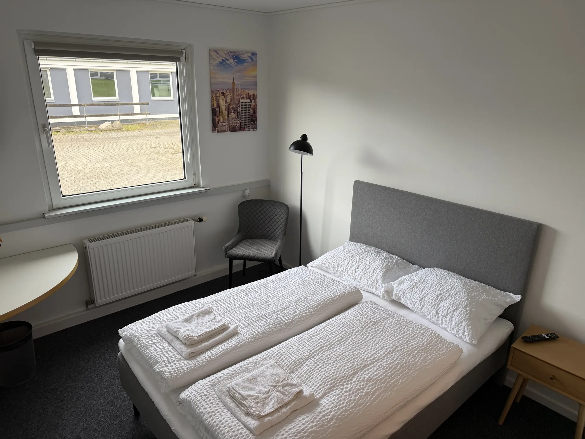 Værelse på Motel Storstrøm med seng, lænestol og vindue mod haven