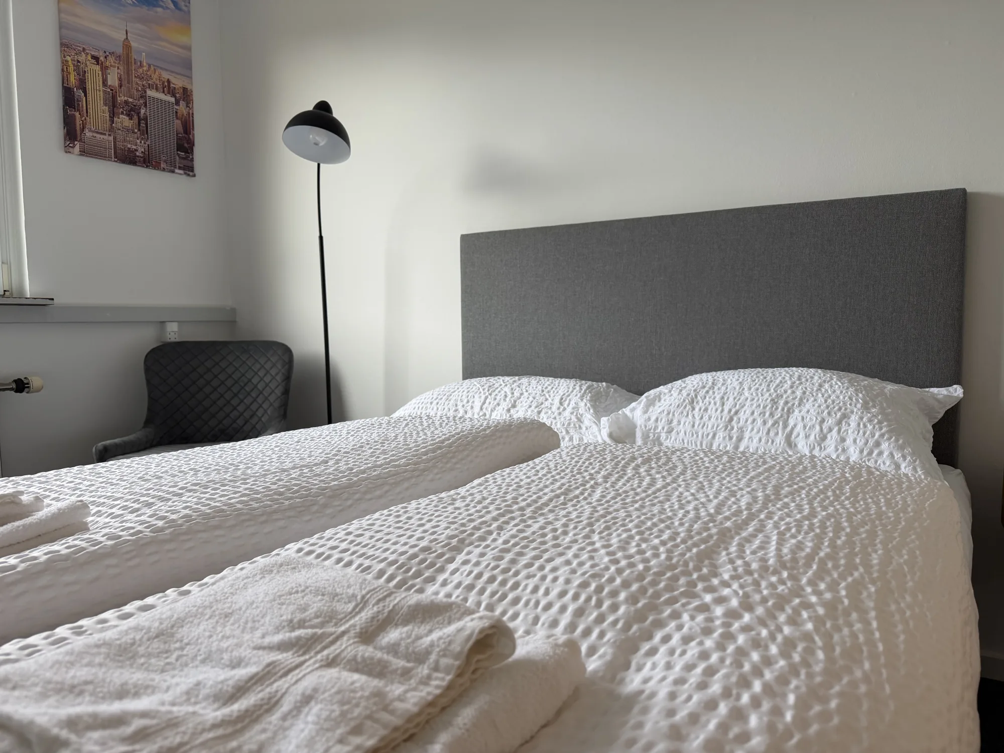 Værelse på Motel Storstrøm med seng, natbordslampe og billede på væggen