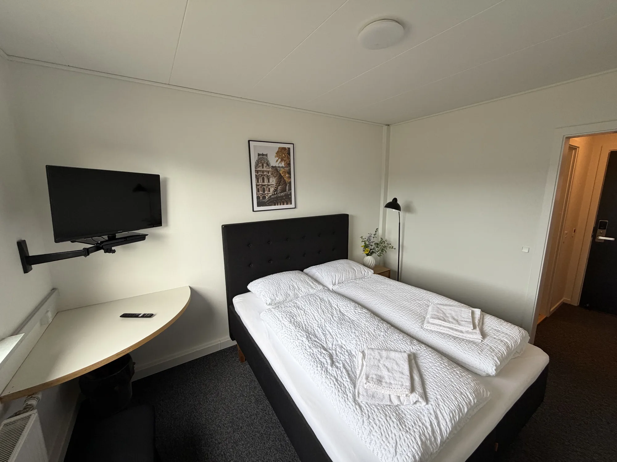 Værelse på Motel Storstrøm med seng, hvidt sengetøj og væghængt tv
