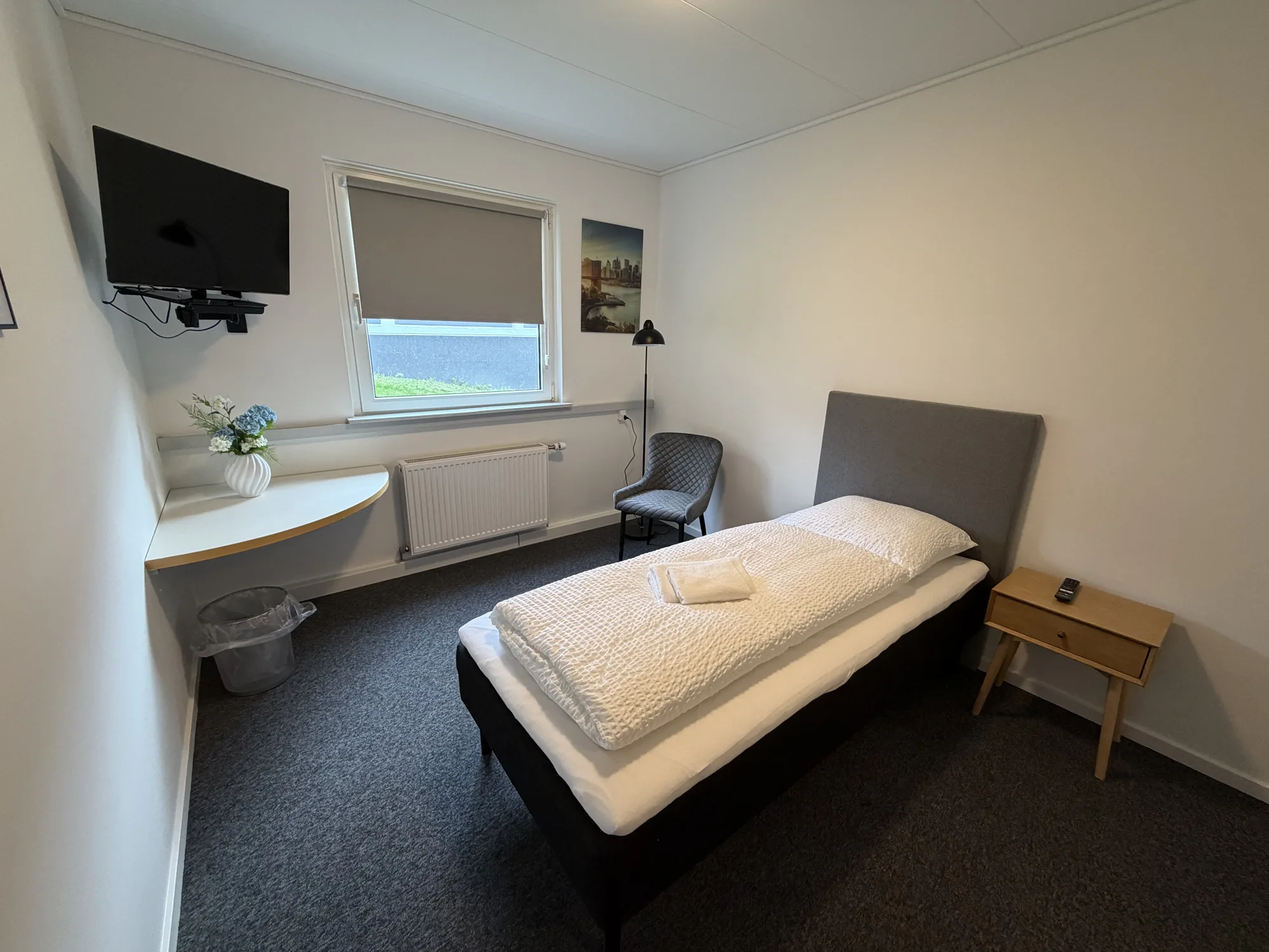 Lyst enkeltværelse på Motel Storstrøm med seng, væghængt tv og vindue