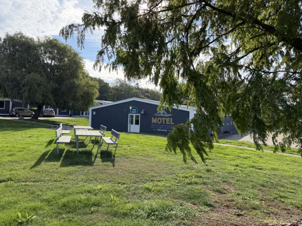 Havebord og stole på græsplænen foran motellet under hængende grene